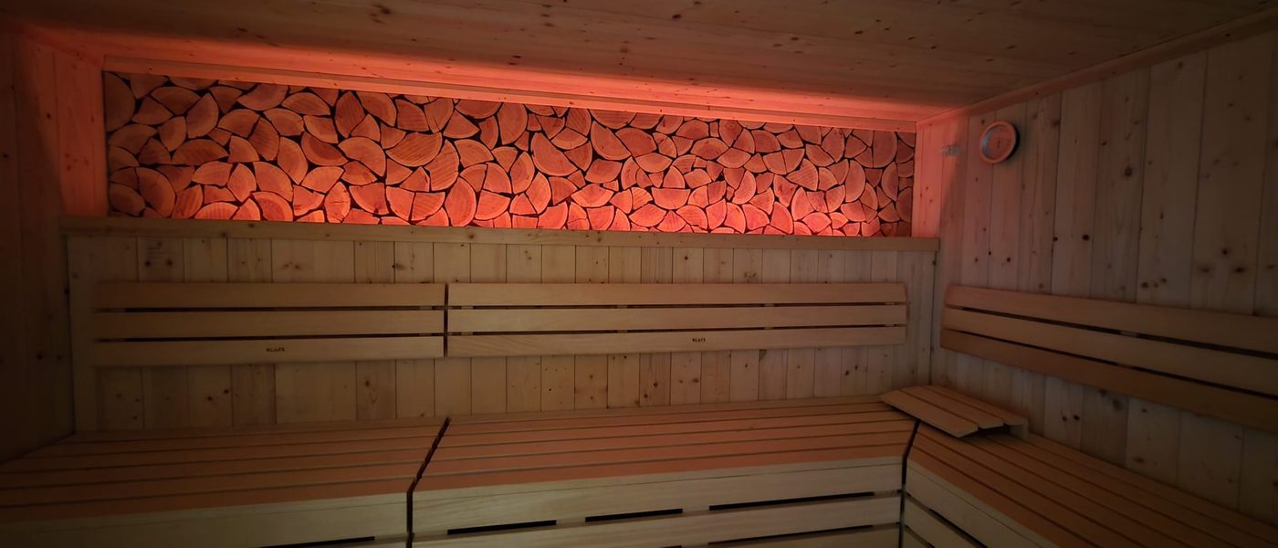 Sauna mit Holzbänken und rotem Farblicht